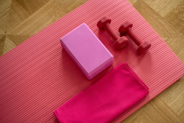 a pink yoga mat, yoga block and light hand weights